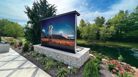 Gran pantalla de cine en un jardín privado, con una foto de un partido de béisbol