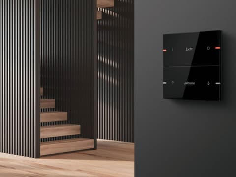 Escaleras de un piso con suelo de madera y un aparato de domótica en la pared
