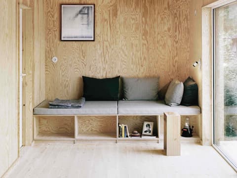 Sofá con estanterías inferiores en una habitación con paredes de madera y domótica en el hogar